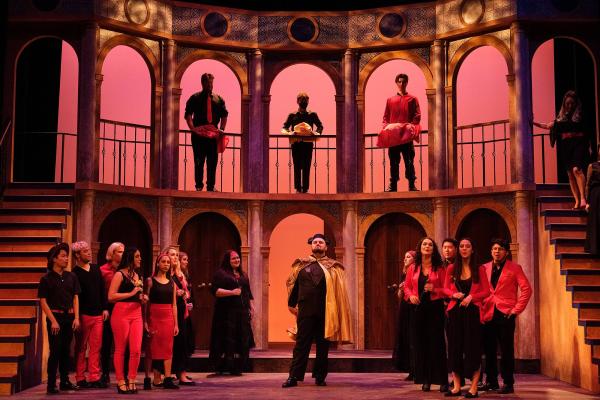 A matador walks confidently across stage while the chorus and cast look on.