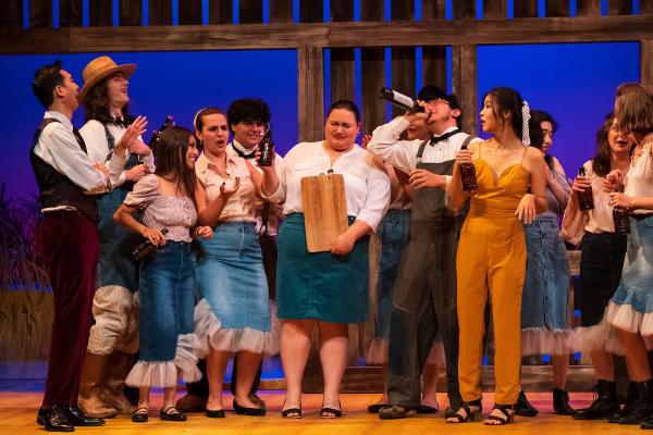 a group of parties at a barn dance raise liquor bottles in celebration