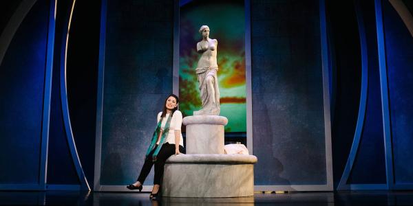 A woman sits at the Statue of Venus, looking off into the distance.