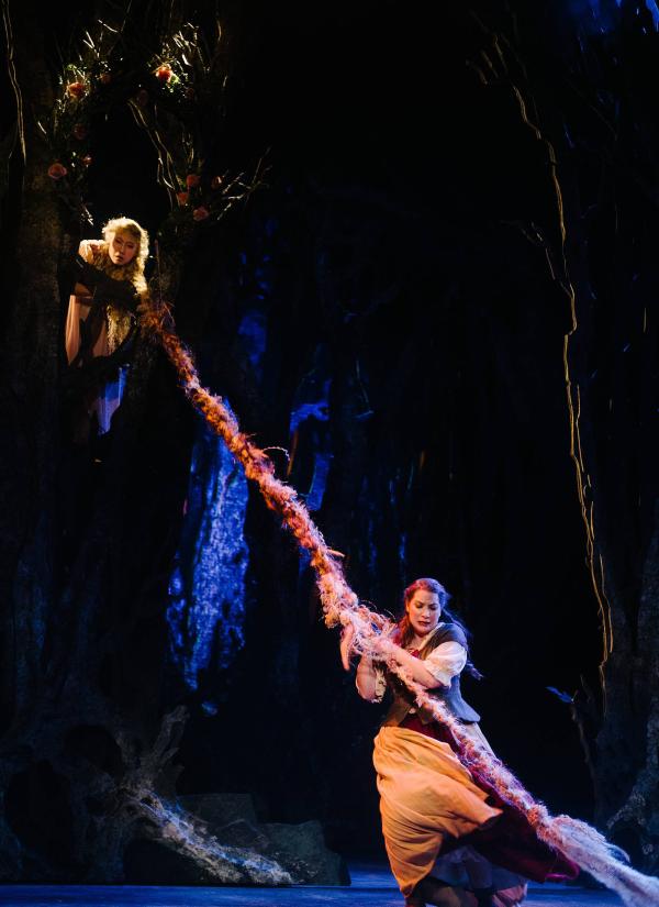 The Baker's wife tugs on the long braided hair of Rapunzel who is locked in a tower high above her on stage.