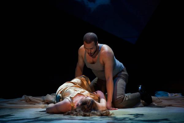 a woman lies unconscious, center stage while a menacing man leans over her. 