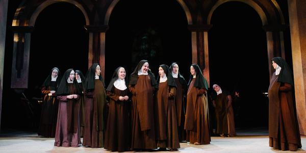 A group of nuns gather on the set of a monastery. 