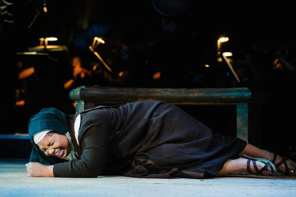 A nun has fallen to the floor and Beats the ground angrily with her fist.