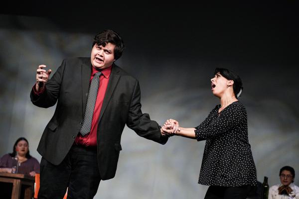 two performers sing together on stage