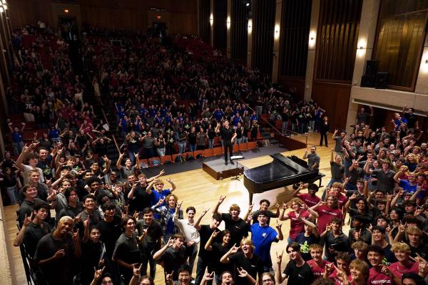 400 students in Bates hall showing the Hook'Em sign