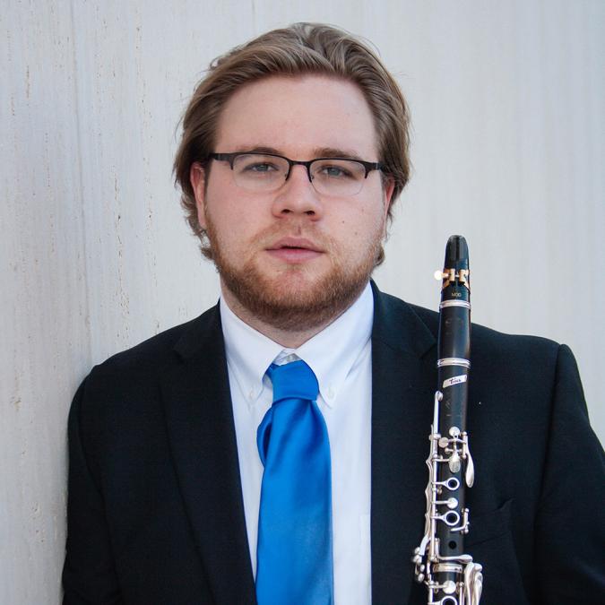 Hank Landrum stands, holding his clarinet looking into camera