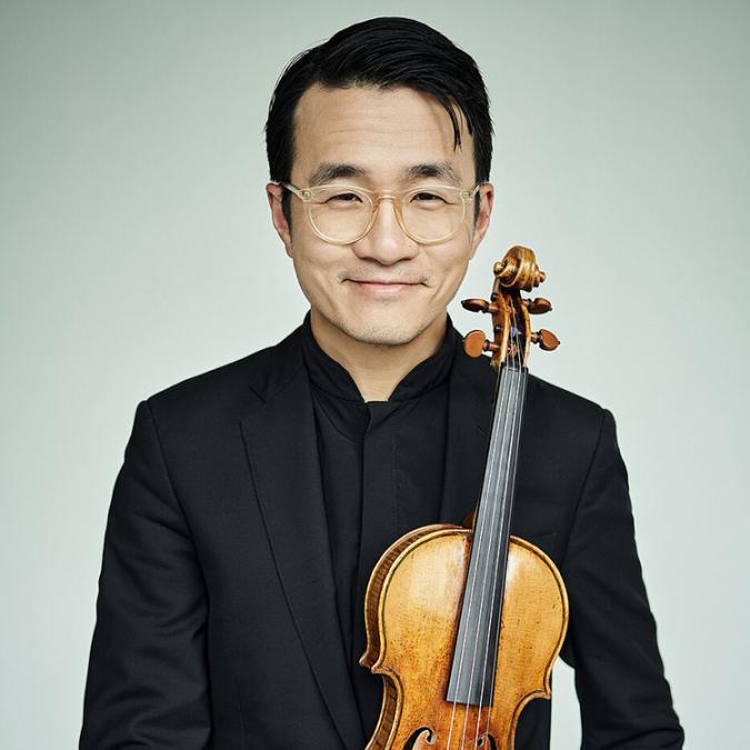 A headshot of Andrew Wan playing his violin. 