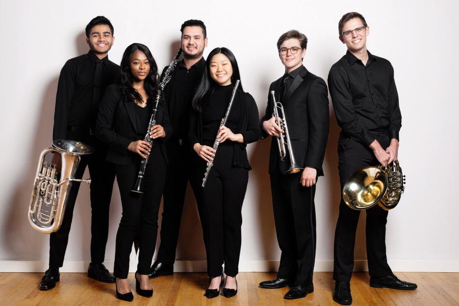 Smiling Members of symphony band in concert attire posing with instruments