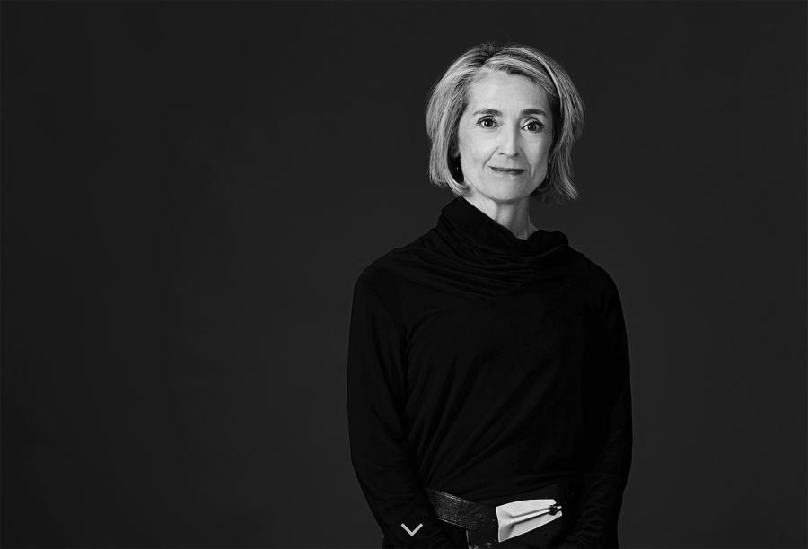 A black and white photo of a blonde woman wearing black with her arms crossed.