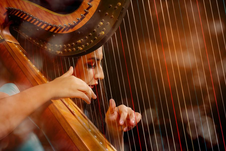 A close up of a harp player plucking the strings during a performance