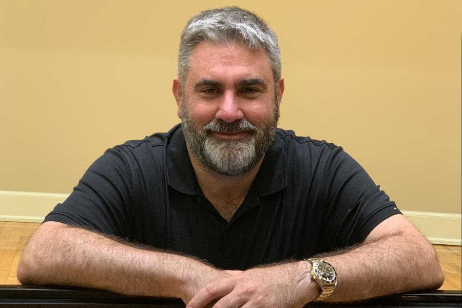 A bearded man wearing a black t-shirt smiles.