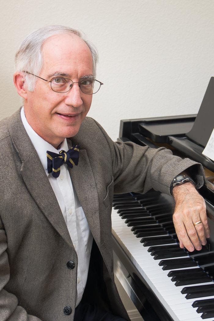 Michael C. Tusa sits at a piano in his office