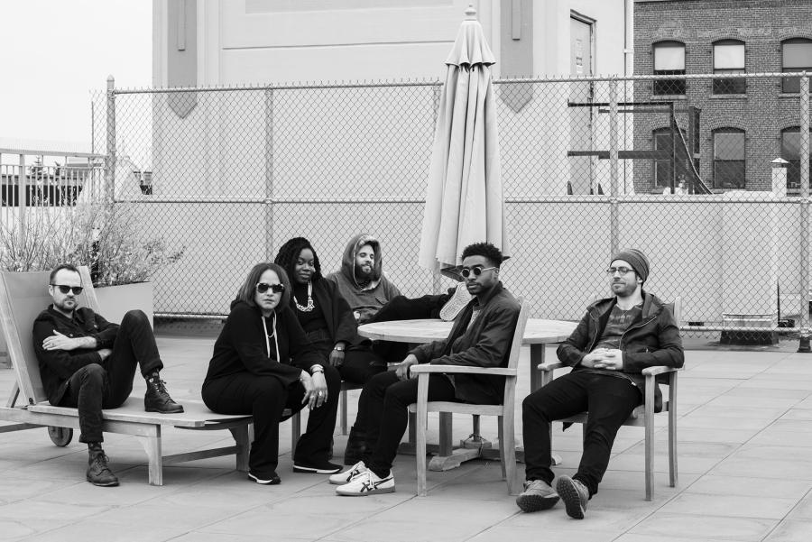 Terri Lynn Carrington and Social Science sit around a table in the courtyard of a downtown cityscape