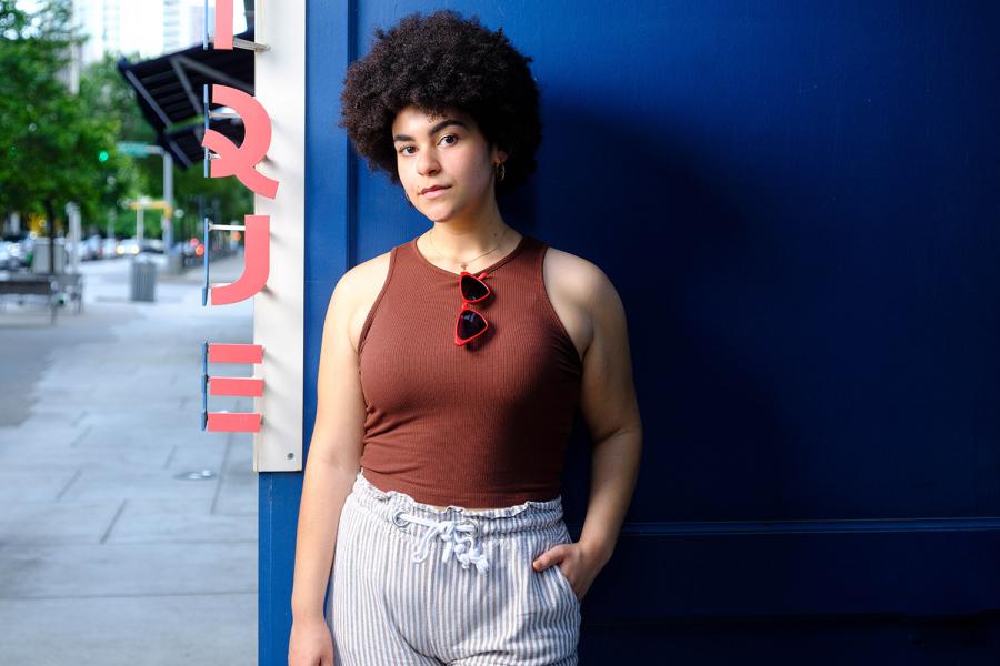 Student Thea Kilbane stands against a blue wall and looks into camera