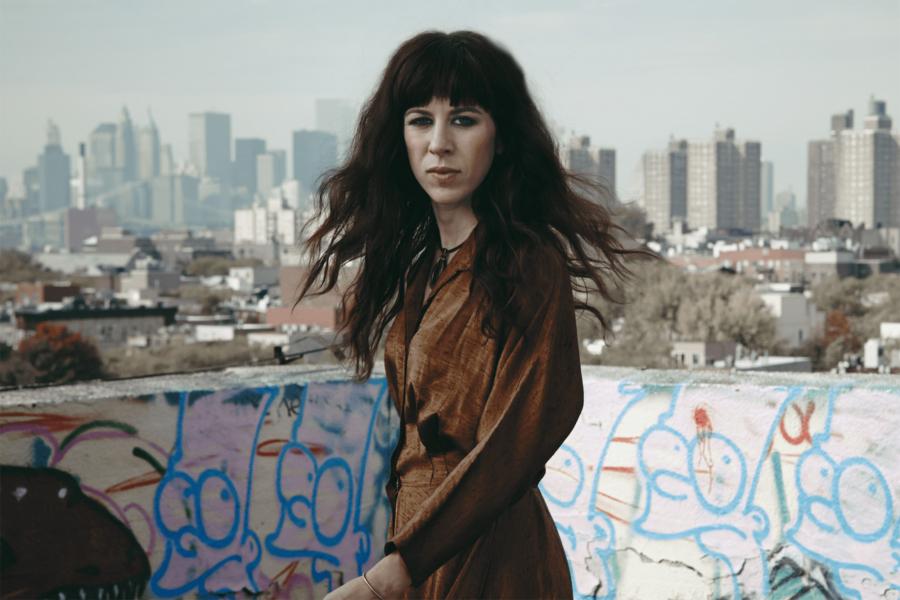 Missy Mazzoli stands in front of urban decay, the New York City skyline in the distant background