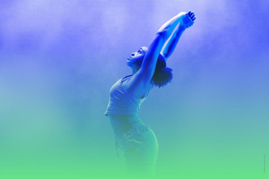 A dancer lifts her arms and arches her back in a hazy green and blue smoky background.