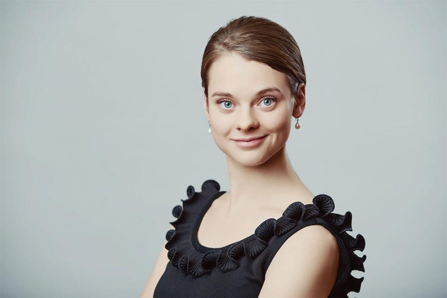 Soprano Rose Hegele smiles at the camera, with her hair pulled back and wearing a ruffly black tank top.