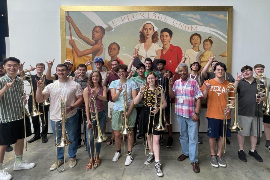 trombone choir poses in front of a work of art.