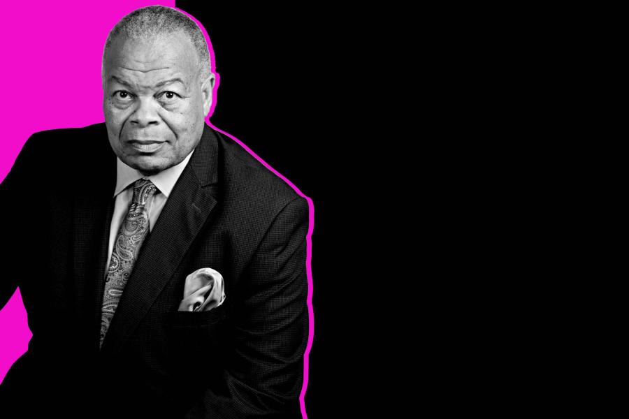 A black and white portrait of baritone Donnie Ray Albert wearing a suit in front of a magenta and black background.