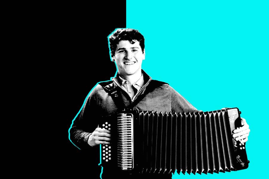 a student plays an accordion while he smiles at the camera