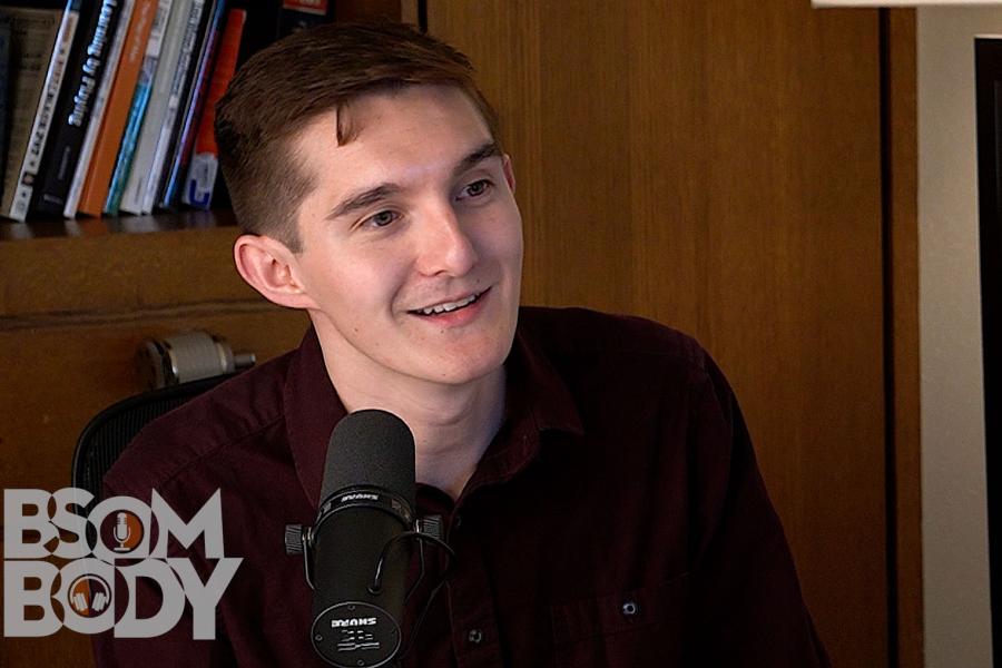 Saxaphonist Jacob Feldman sitting behind a mic with a bookshelf in the background