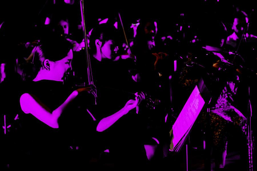 Neon purple photo of the UT New Music Ensemble in concert.
