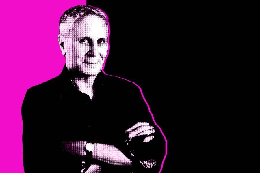 Black and white photo of composer John Corigliano in front of a black and magenta background.