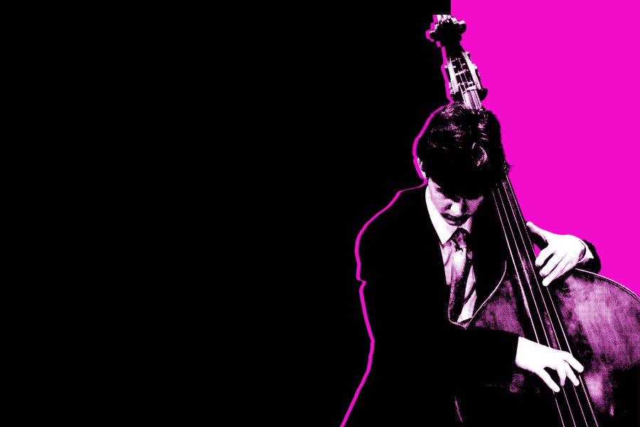 Black and white photo of a student playing the upright bass in front of a magenta and black background.