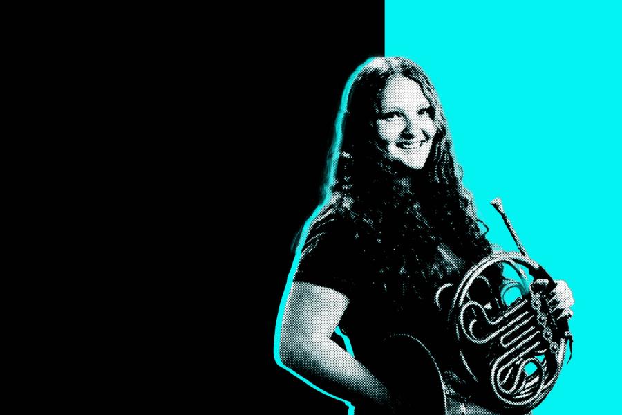 Black and white photo of a student holding a french horn in front of a black and aqua background.