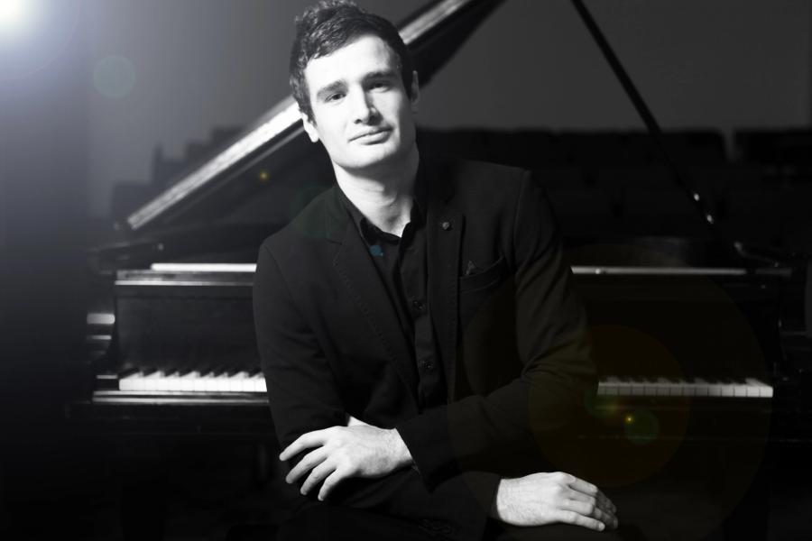 Artem Kuznetsov sitting in front of a piano