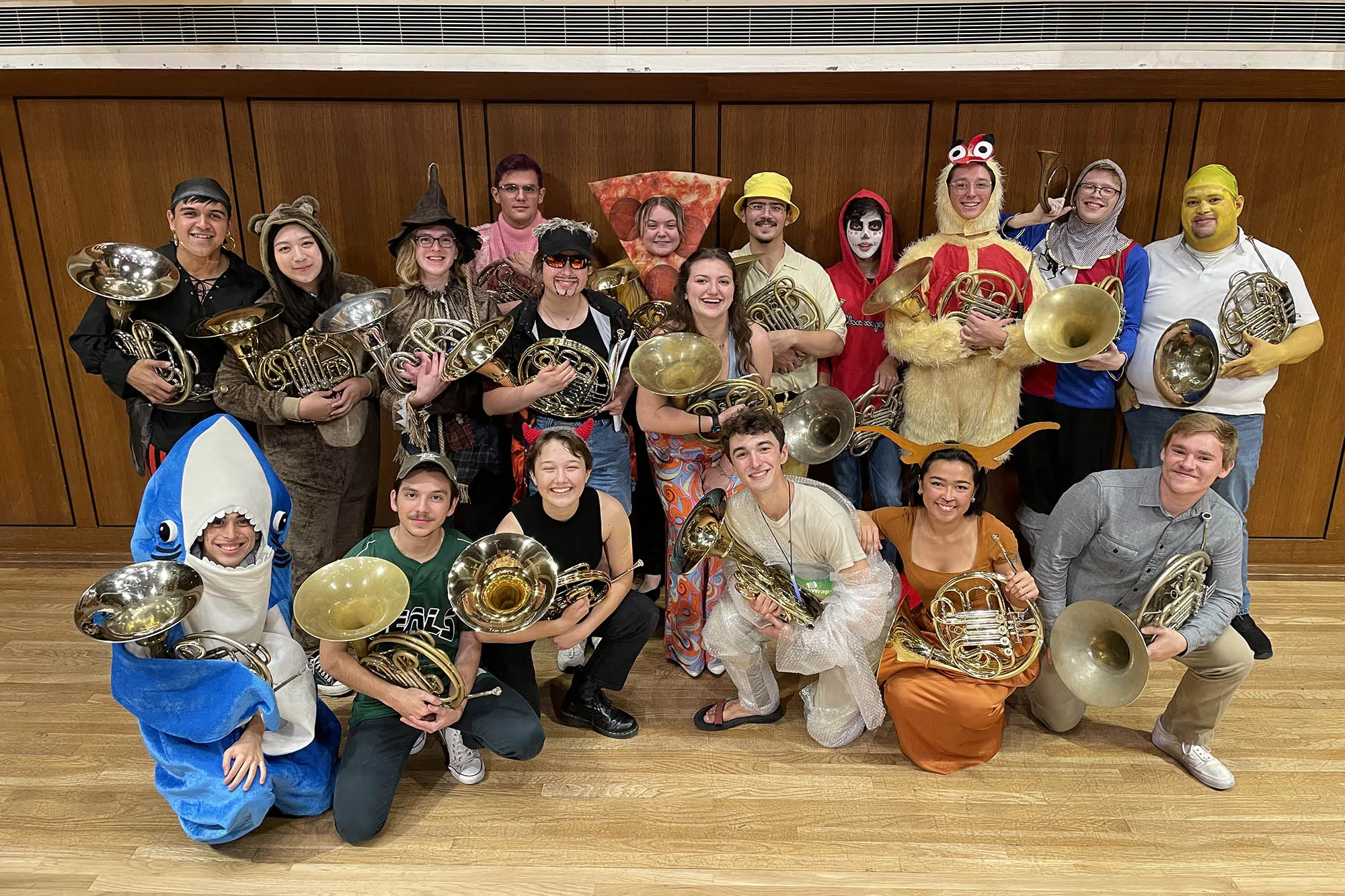 The horn studio, all dressed in Halloween costumes, pose for a group photo on the Bates Recital Hall stage after a concert.