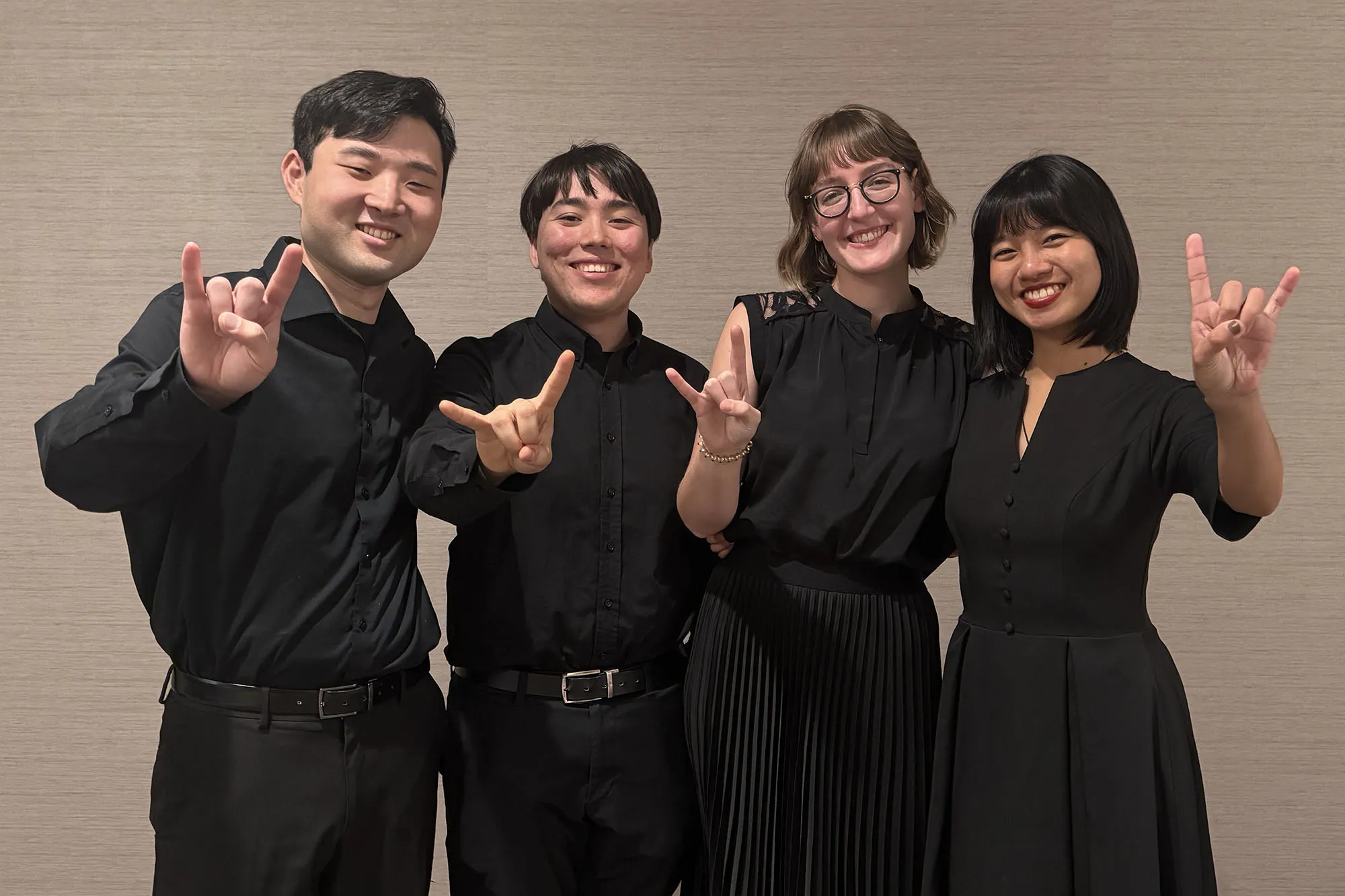 Soha quartet Mei Liu (violin), Chloe Yofan (violin), Thomas Gougeon (viola), and Katusaki Arakawa (cello) showing the hook em sign