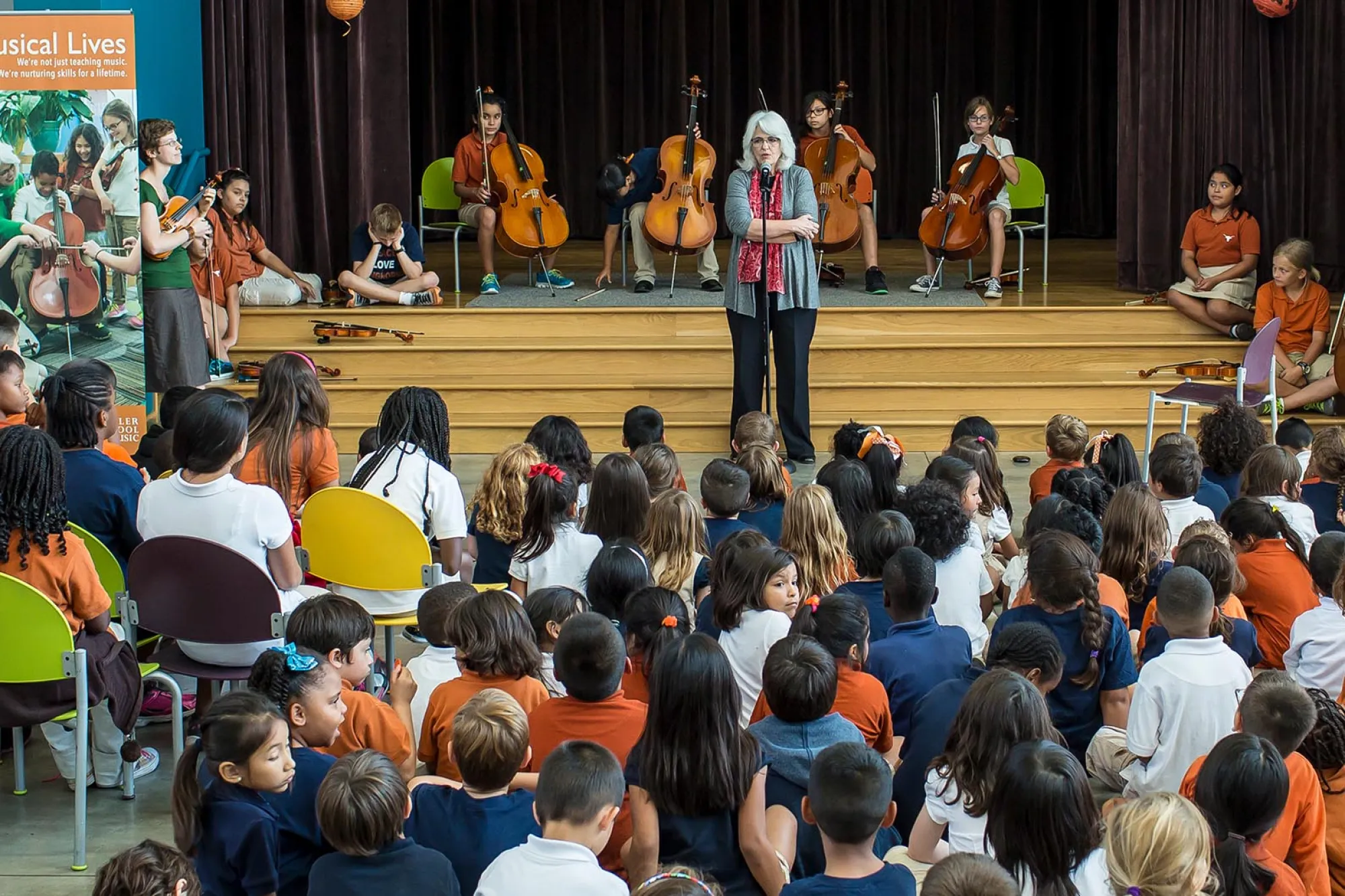 Laurie Scott on stage talking to a group of school children