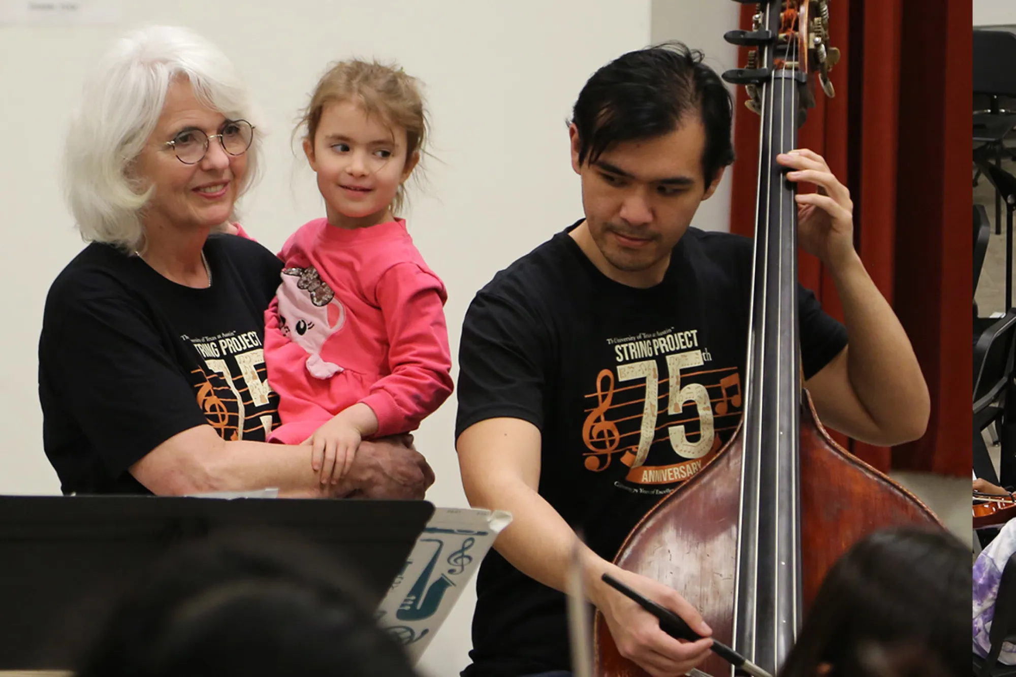 Laurie Scott holds a child and shows that child a Bass