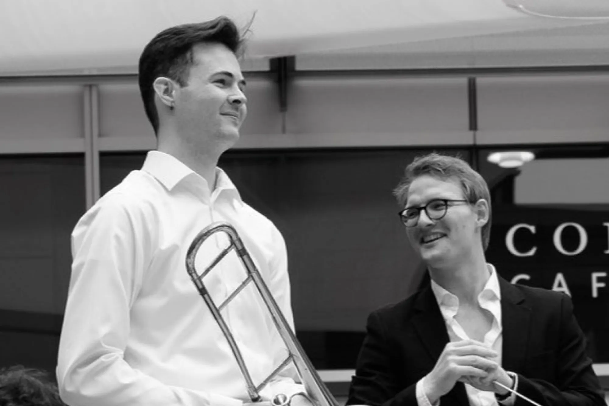 Dillon MacIntyre standing with a trombone with a person next to him