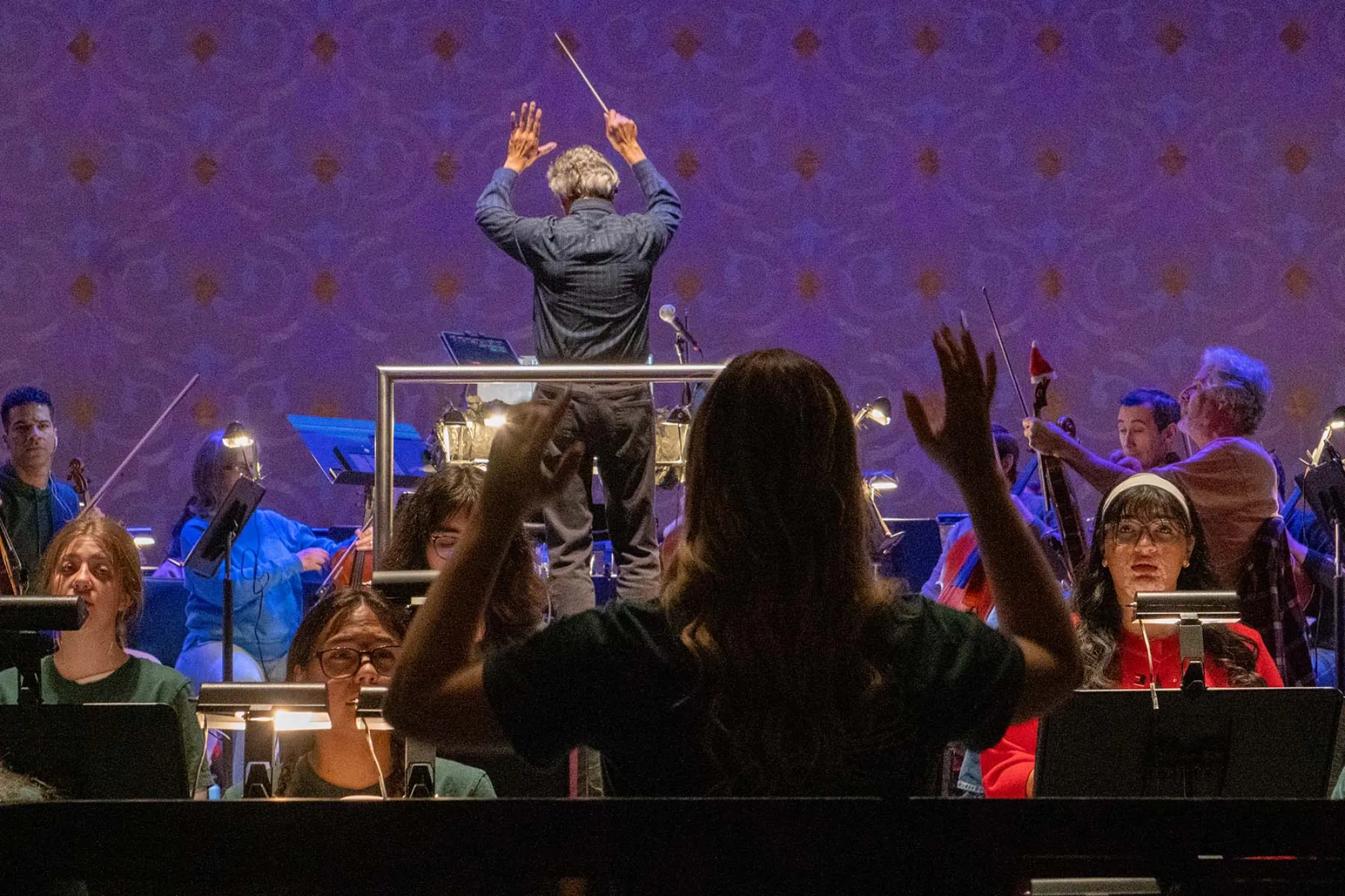 Two conductors conduct with their back to the camera