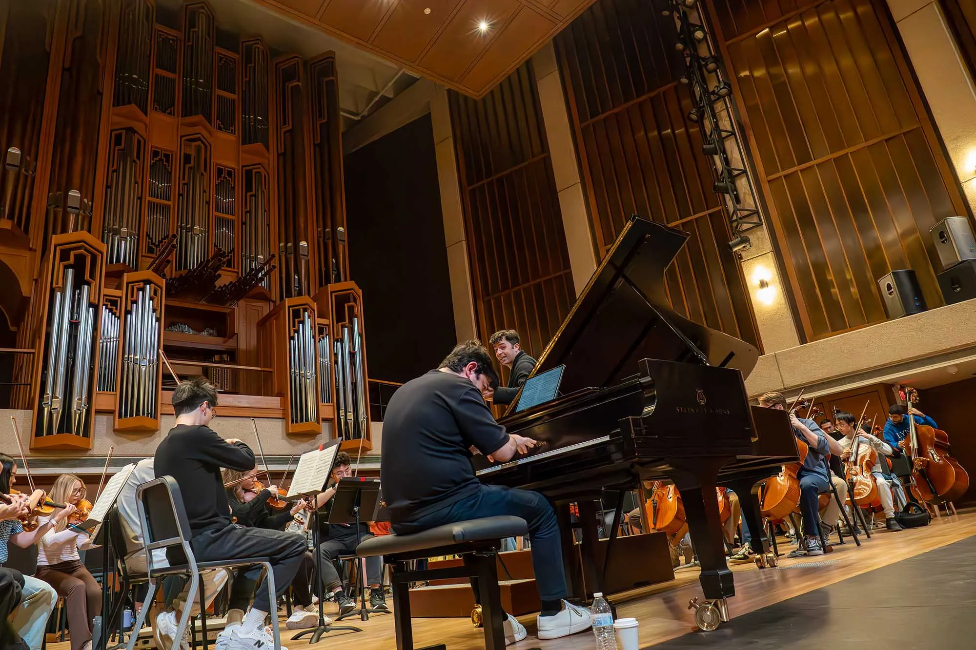 conductor  Farkhad Khudyev with Behzod Abduraimov on piano on stage in front of an orchestra