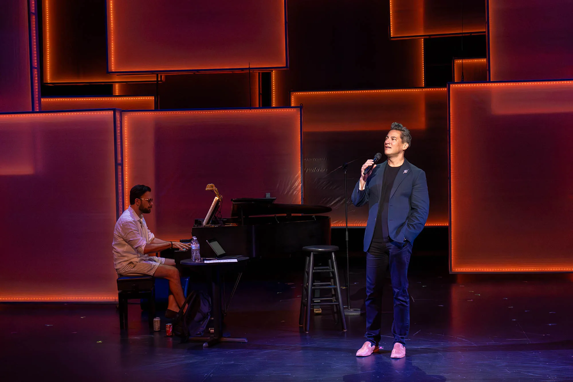 Nicholas Rodriguez singing on stage with a piano in the background