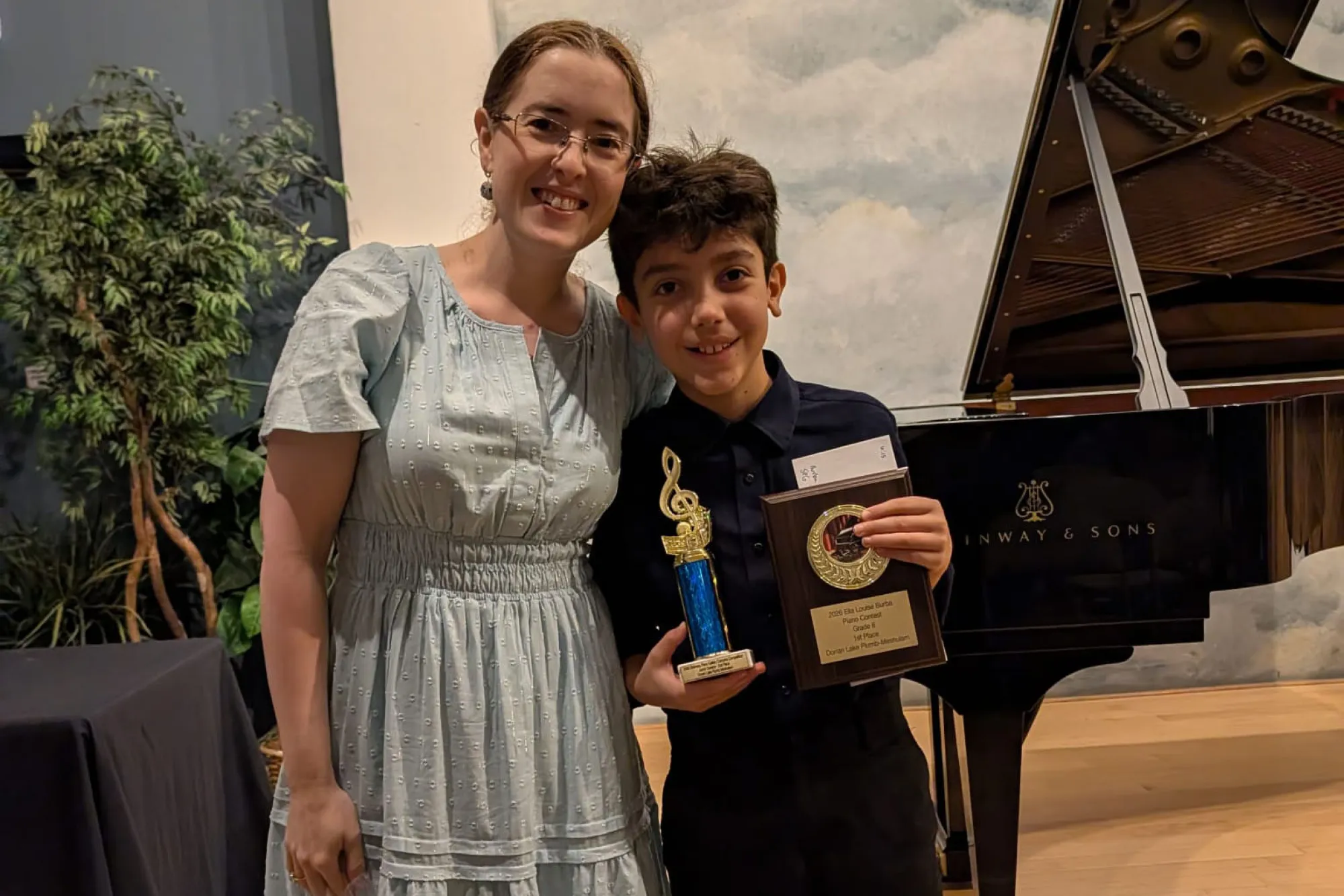 Margarita Denenburg standing next to a student while holding an award