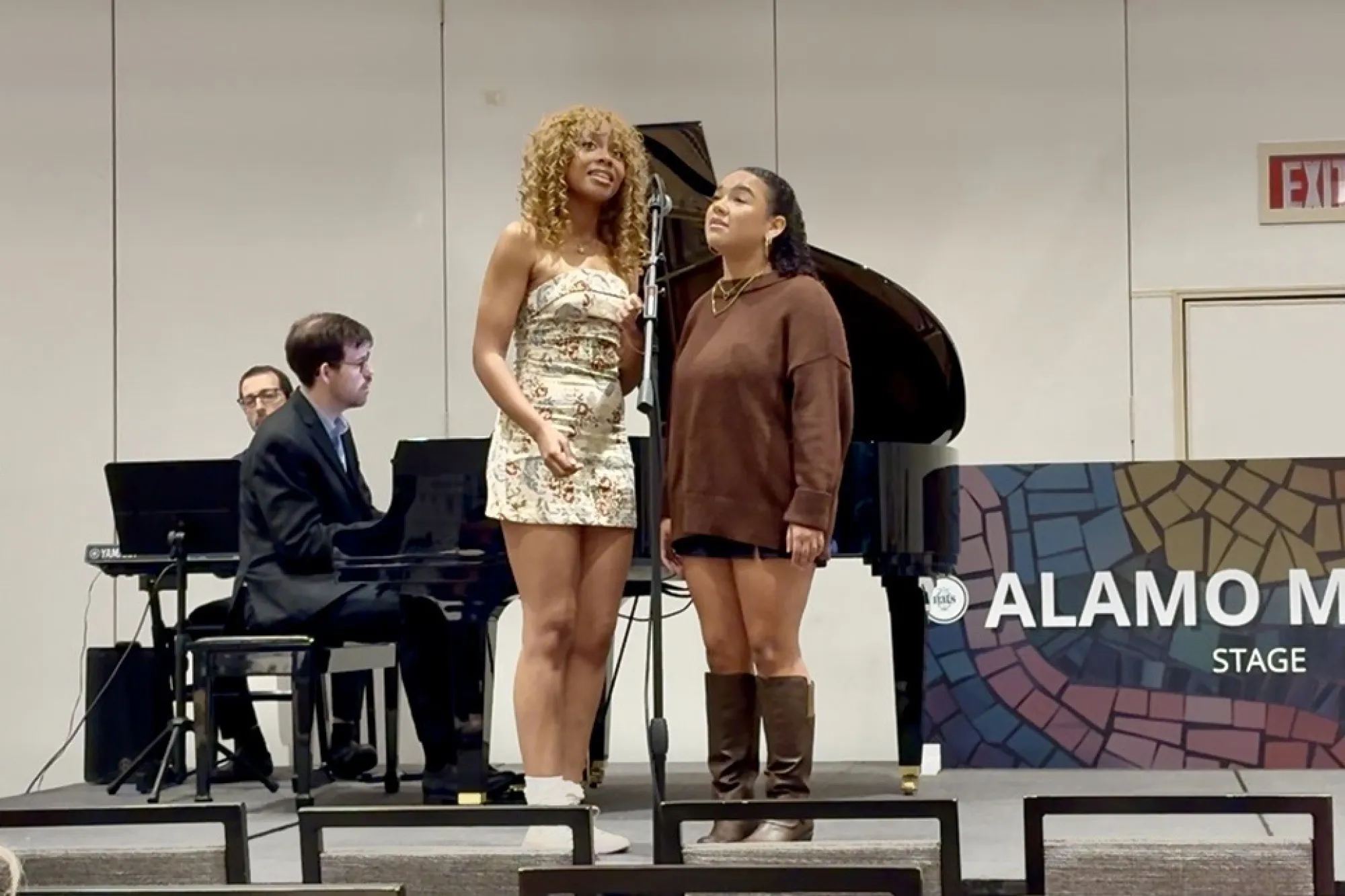 College students sing on stage with a piano in the background