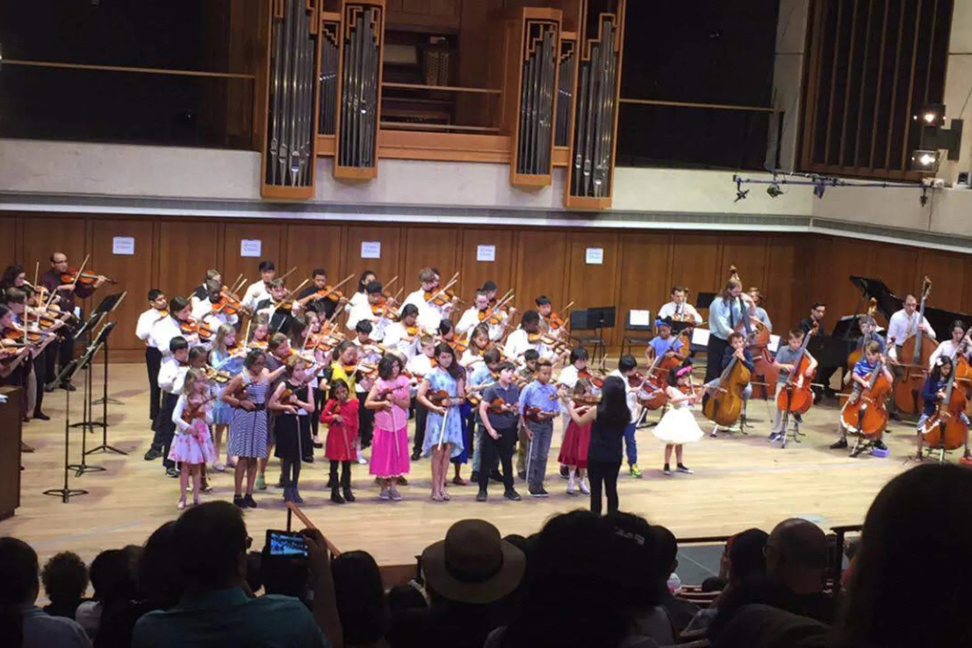 A large group of children perform music on stage