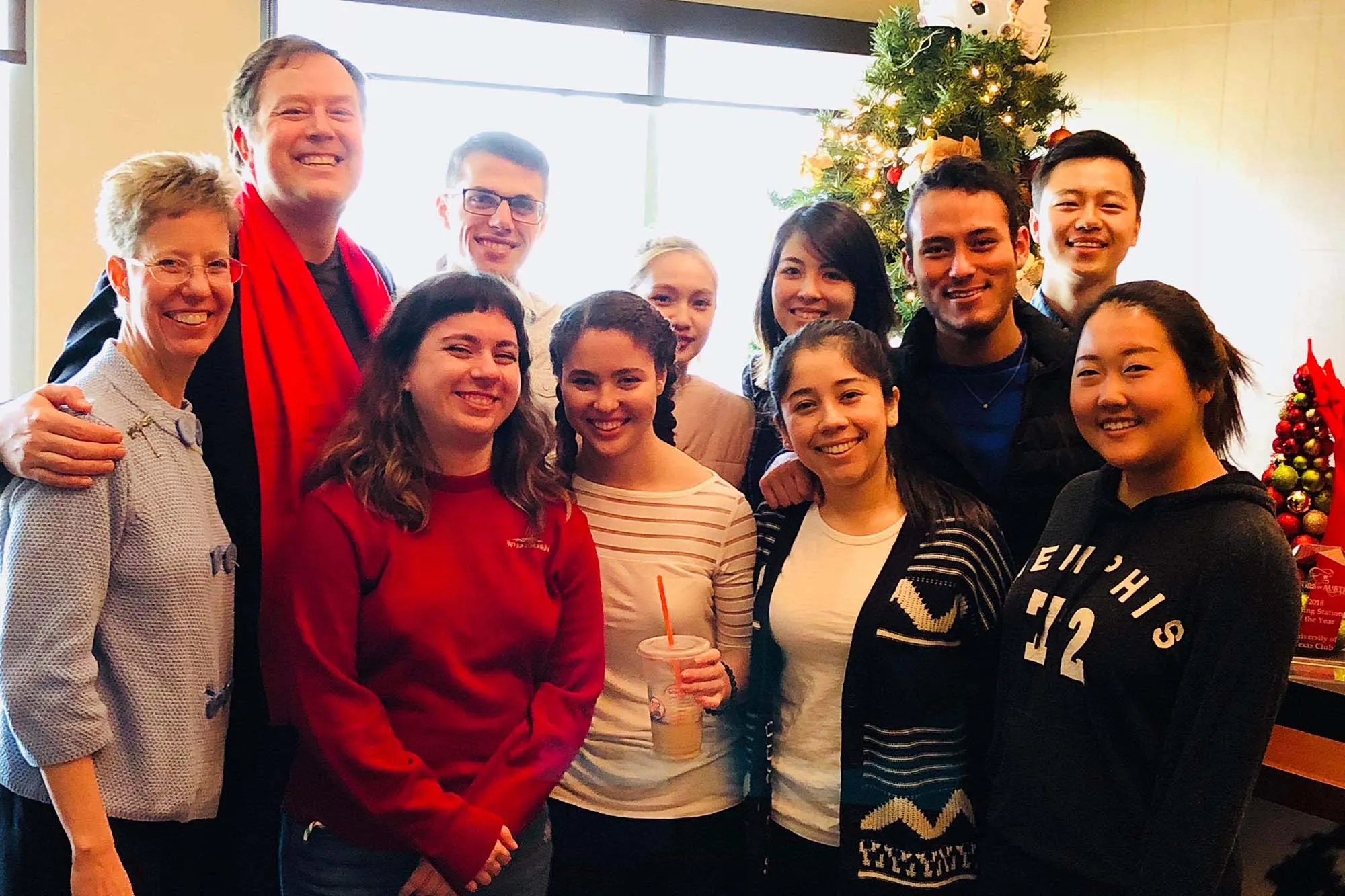 A group of people smile with a christmas tree behind them