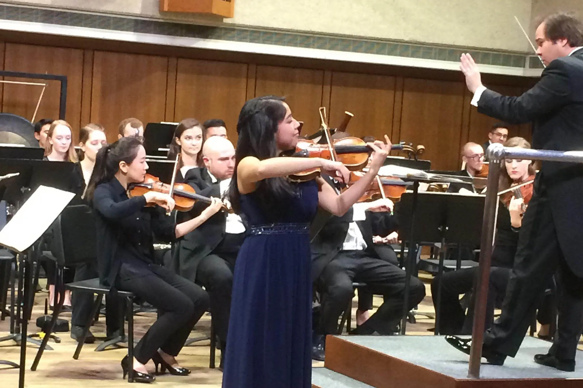A violinist performs in front of an orchestra