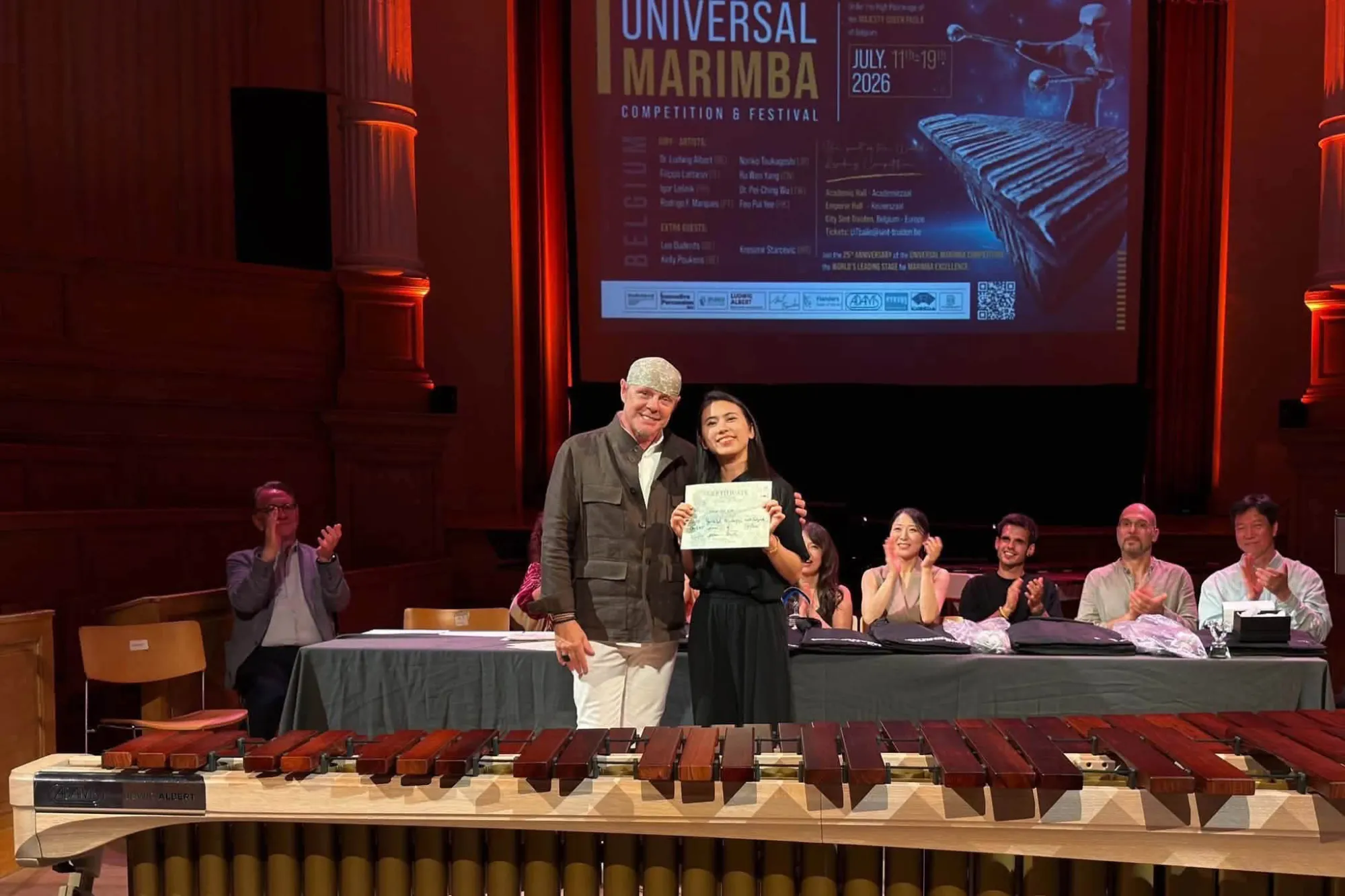 Two people stand on stage holding an award