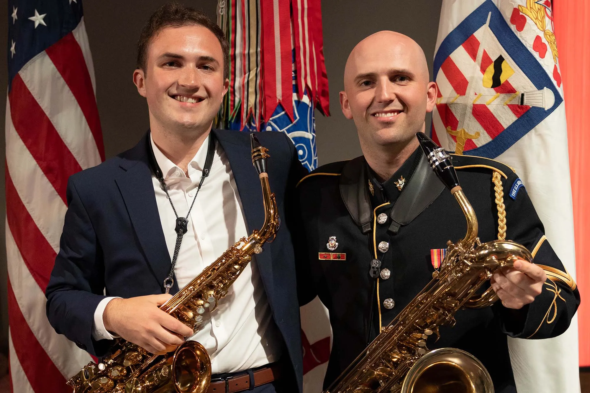 Andrew Stine and his brother hold saxaphones and stand in front of United States flags