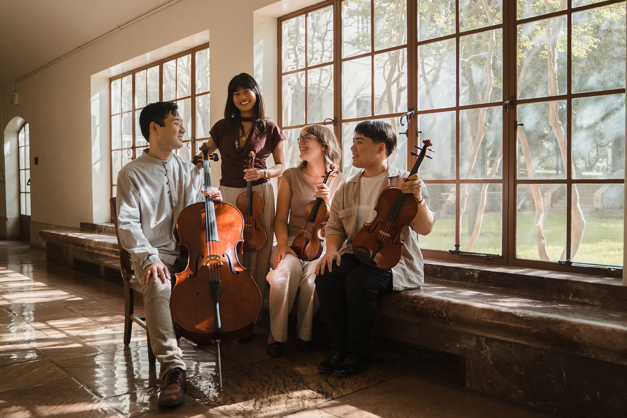the members of soho Quartet sit with their instruments in a sun-lit hall