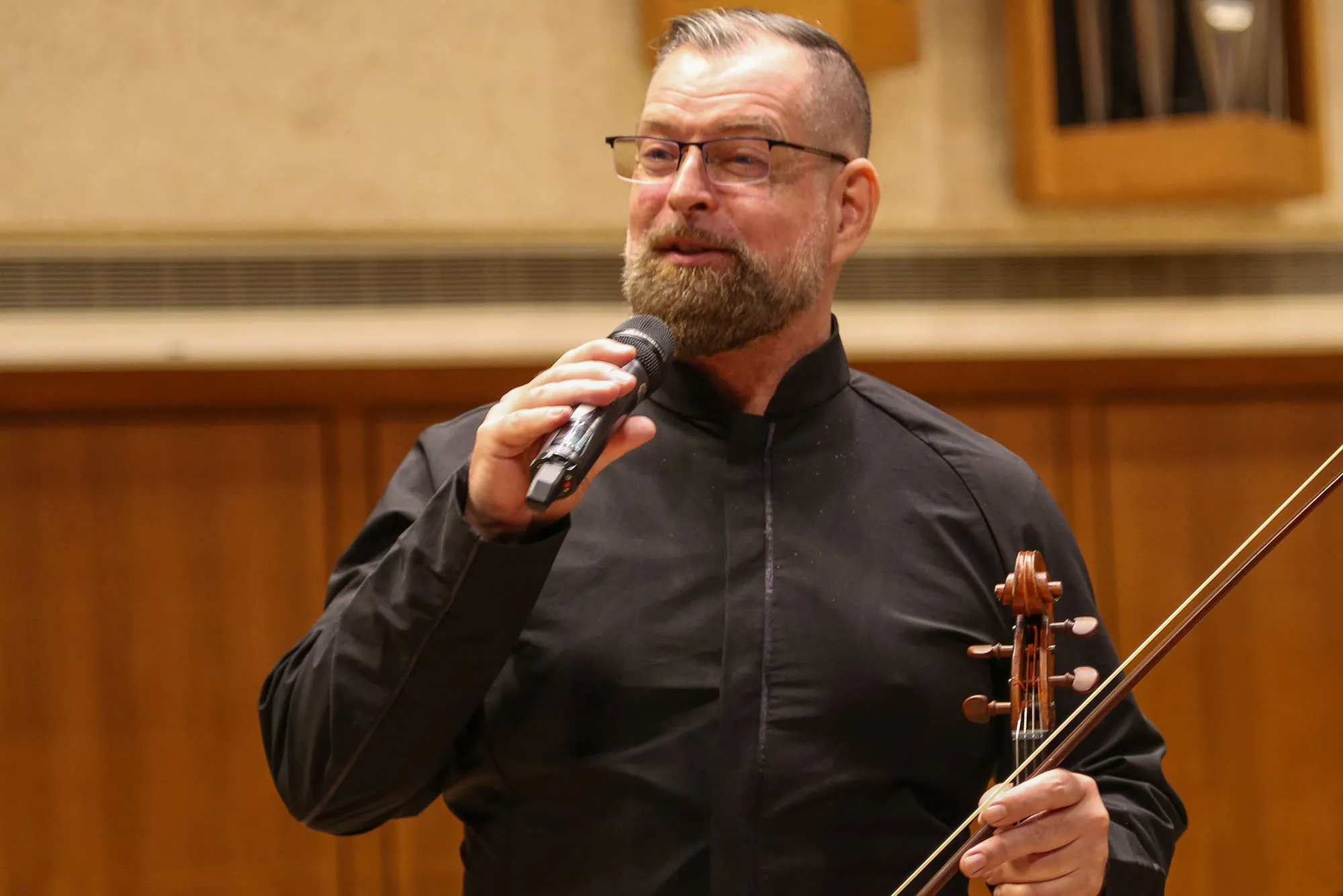 A musician stands on stage and talks in a mic