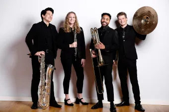 A group of Wind Symphony players holding instruments and laughing.