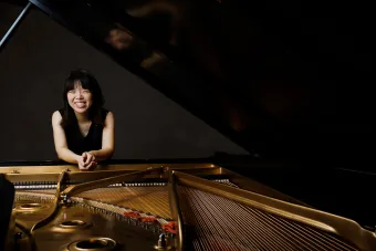 A Pianist smile into the camera from a Piano.