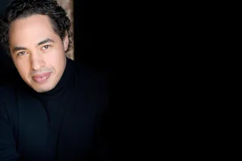 A man wearing a black turtle neck smiles at the camera.